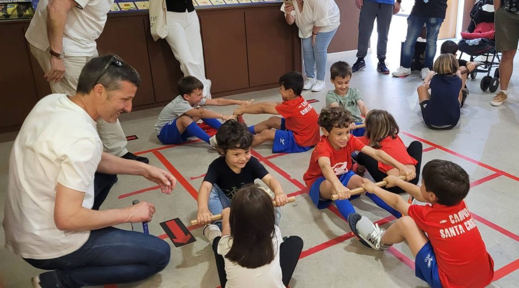 Niños del Santa Cruz CF vigilados por un padre juegan en el Museo MELGA a un juego tradicional