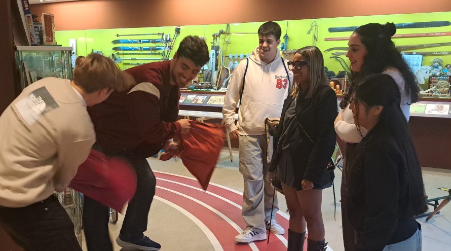Dous alumnos xogan a xogos populares no Museo MELGA ante a mirada e risas dos seus compañeiros